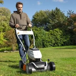a man mowing a lawn with a STIHL RMA 2 R Cordless Mulching Lawn Mower