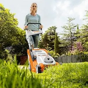 a woman mowing a lawn using a STIHL lawnmower