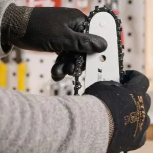 someone wearing black gloves, holding a chainsaw guide bar