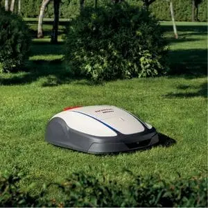 a Honda Miimo 1000 Robotic Mower on a lawn, in front of some shrubs