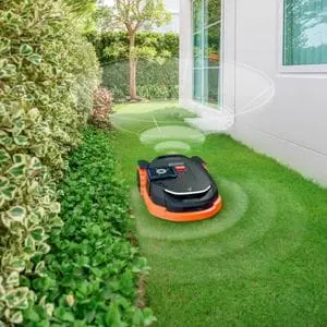 a Segway Navimow robotic mower navigating a narrow passageway between a house and hedge